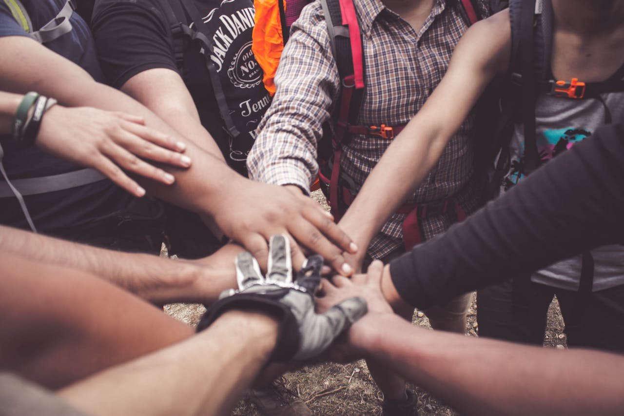 A group of diverse individuals join hands for teamwork in West Java, Indonesia.